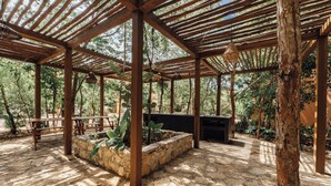 An outdoor patio area with a pergola structure, stone planters, and a built-in barbecue station. - Aldea Savia hideaway in Tulum (Tulum)