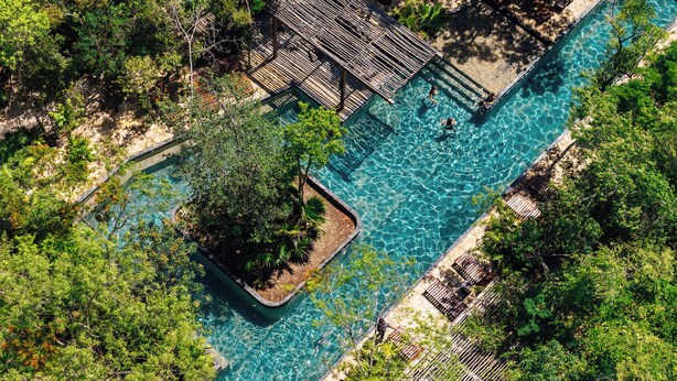 An aerial view of a rectangular swimming pool with clear blue water, surrounded by lush greenery and a wooden deck. - Aldea Savia hideaway in Tulum (Tulum)
