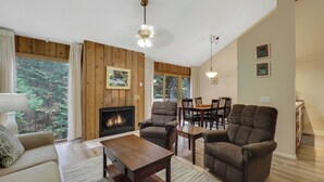 Una sala de estar acogedora con chimenea, paredes de madera y un comedor con sillas y una mesa.