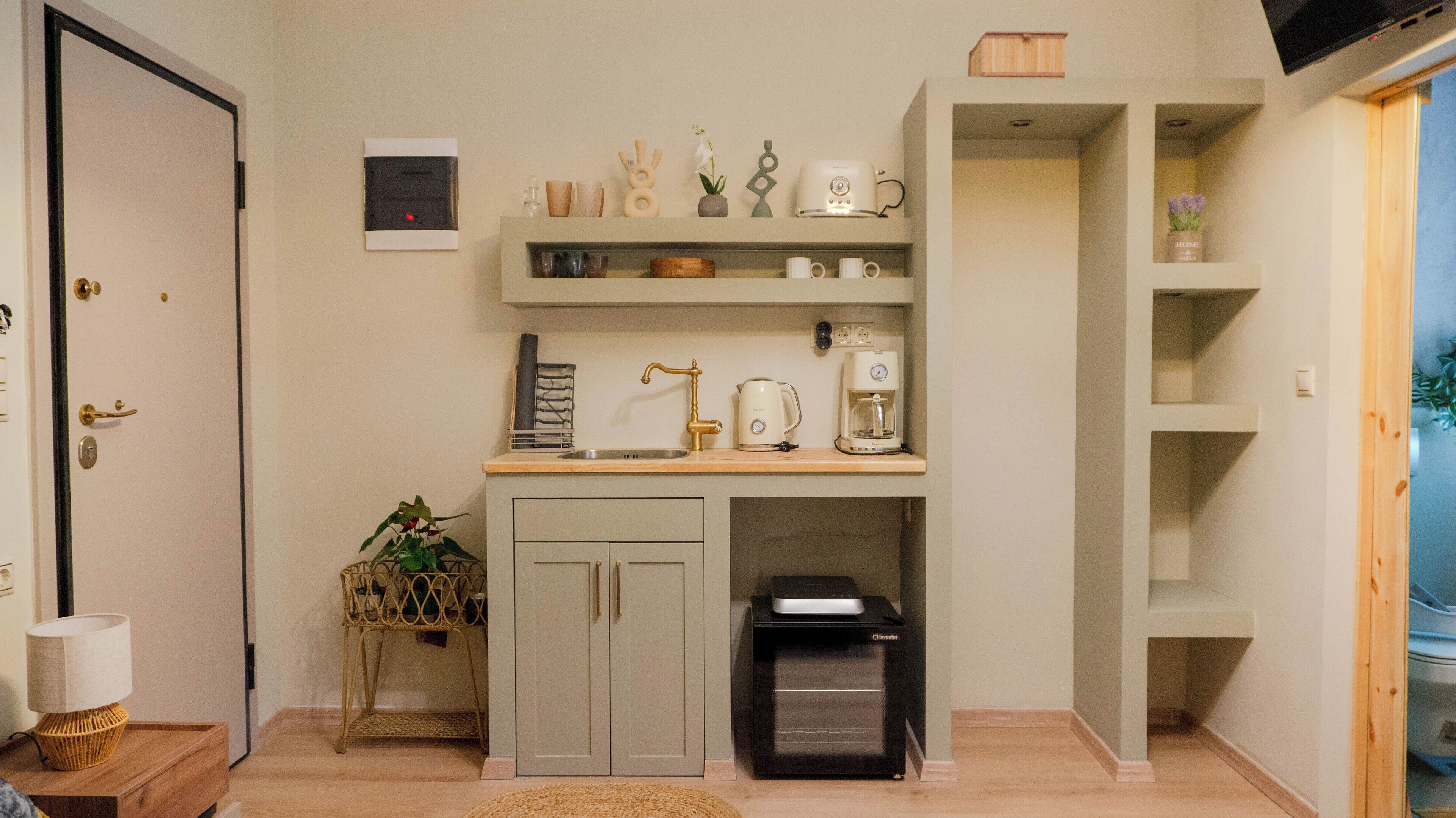 A compact kitchen with a built-in oven, a coffee maker, and a trash bin.