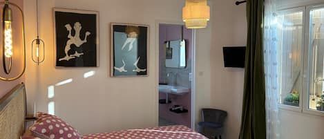 A bedroom with a bed, a bedside table, a mirror, and a window with curtains.