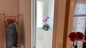A bathroom with a white toilet, a wooden drying rack with clothes, and a mirror with a vase of flowers. - La CAMARGUAISE Room Breakfast included. SOL en CIEL house. (Aigues-Mortes)