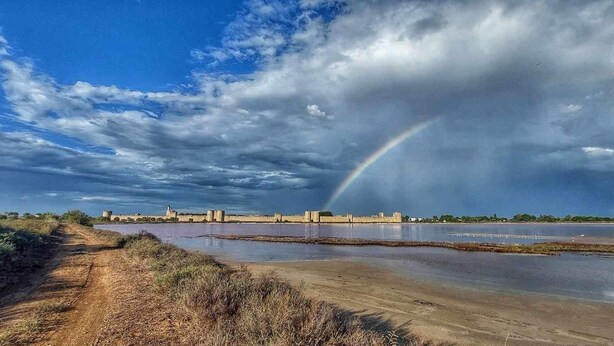 A coastal landscape with a rainbow, a sandy path, and a distant castle. - La CAMARGUAISE Room Breakfast included. SOL en CIEL house. (Aigues-Mortes)