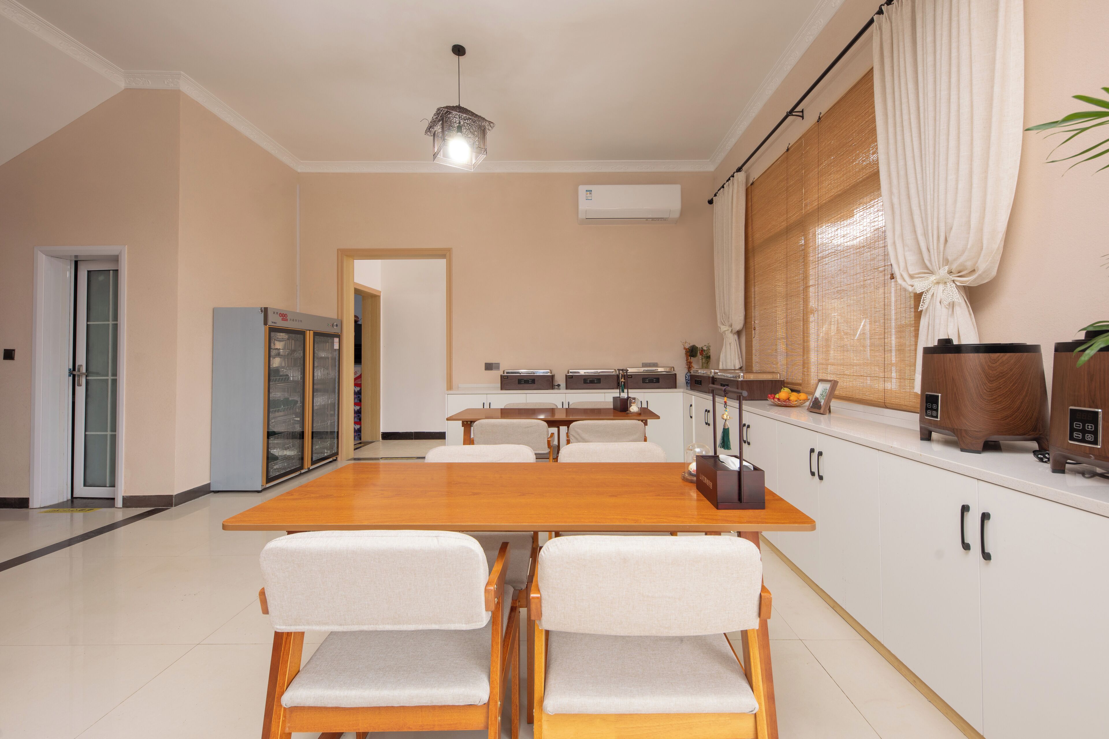 A modern kitchen with a wooden dining table, white chairs, and a built-in oven.