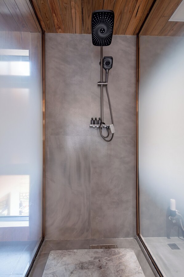 Une douche moderne dotée d’un pommeau de douche à main et d’un ventilateur fixé au mur.