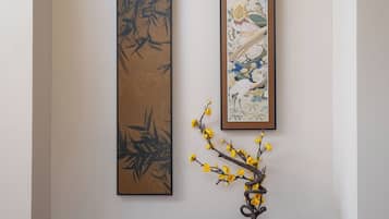 Una pared con dos cuadros enmarcados y un jarrón con flores amarillas sobre una mesa de madera oscura.