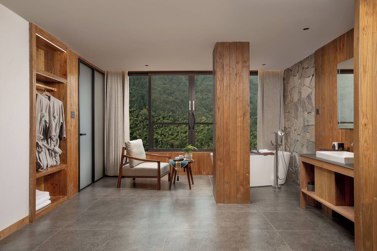A modern bathroom with a bathtub, a sink, and a large window offering a view of the outdoors.