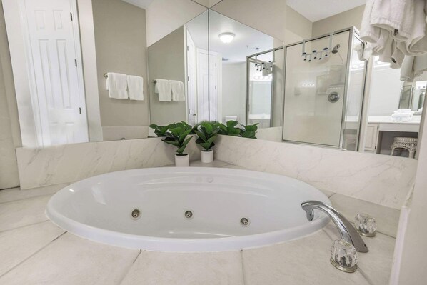 A modern bathroom with a large oval bathtub, a glass-enclosed shower, and a large mirror. - Grand Pointe 310 Panoramic Views Huge Balcony (Orange Beach)