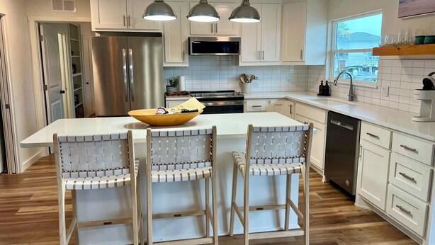 A modern kitchen with white cabinets, stainless steel appliances, and a central island with bar stools. - The Boat House:  Key Allegro, Water Front, On Canal! (Rockport)