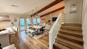 A spacious living area with a wooden staircase, a dining table, and a kitchen area with a view to the outside. - The Boat House:  Key Allegro, Water Front, On Canal! (Rockport)