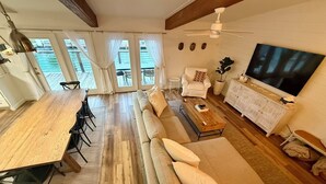 A spacious living area with a wooden dining table, a sofa, a coffee table, a TV, and a ceiling fan. - The Boat House:  Key Allegro, Water Front, On Canal! (Rockport)