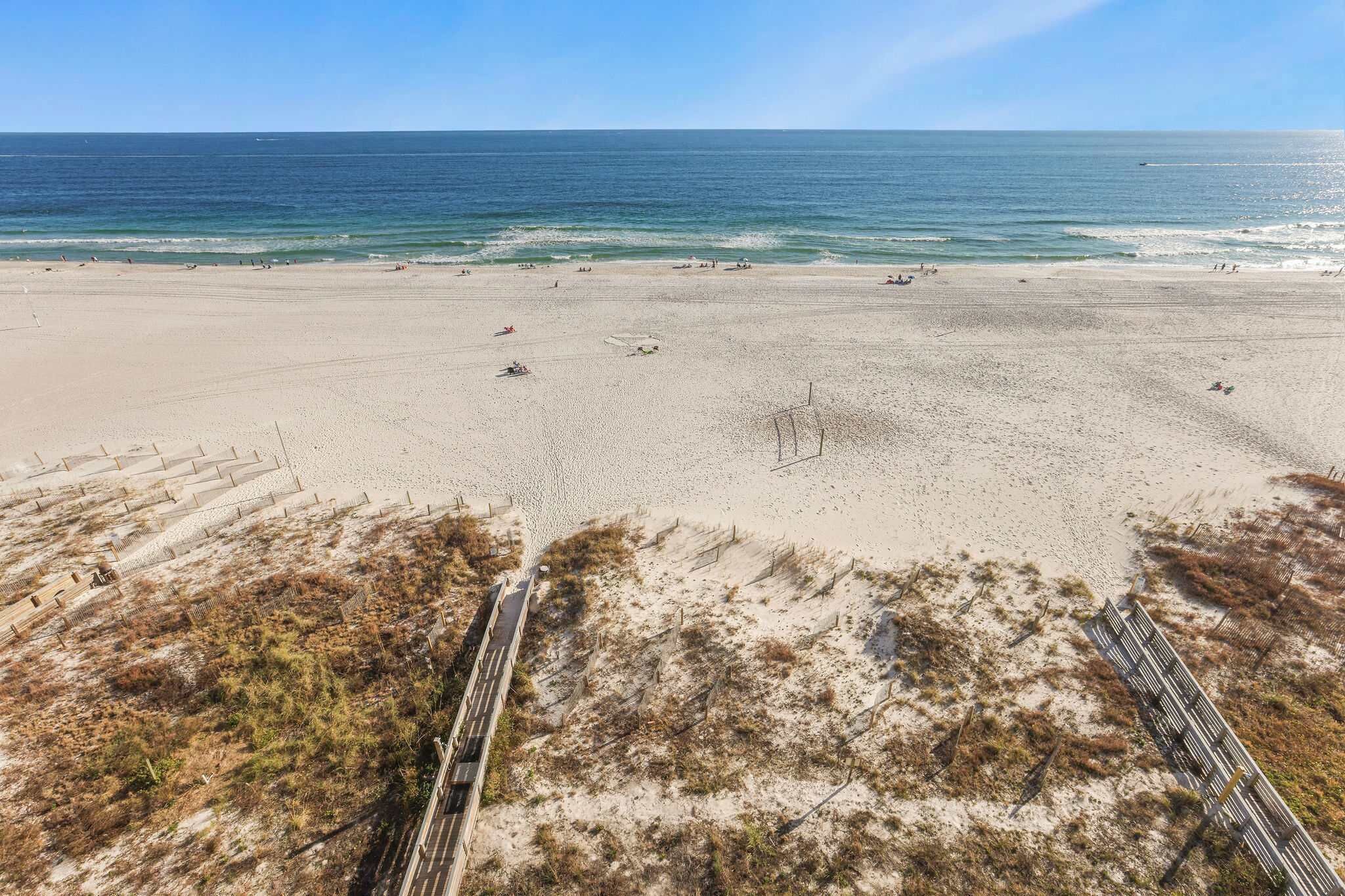 A beach with a clear view of the ocean, sandy terrain, and a pathway leading to the water.