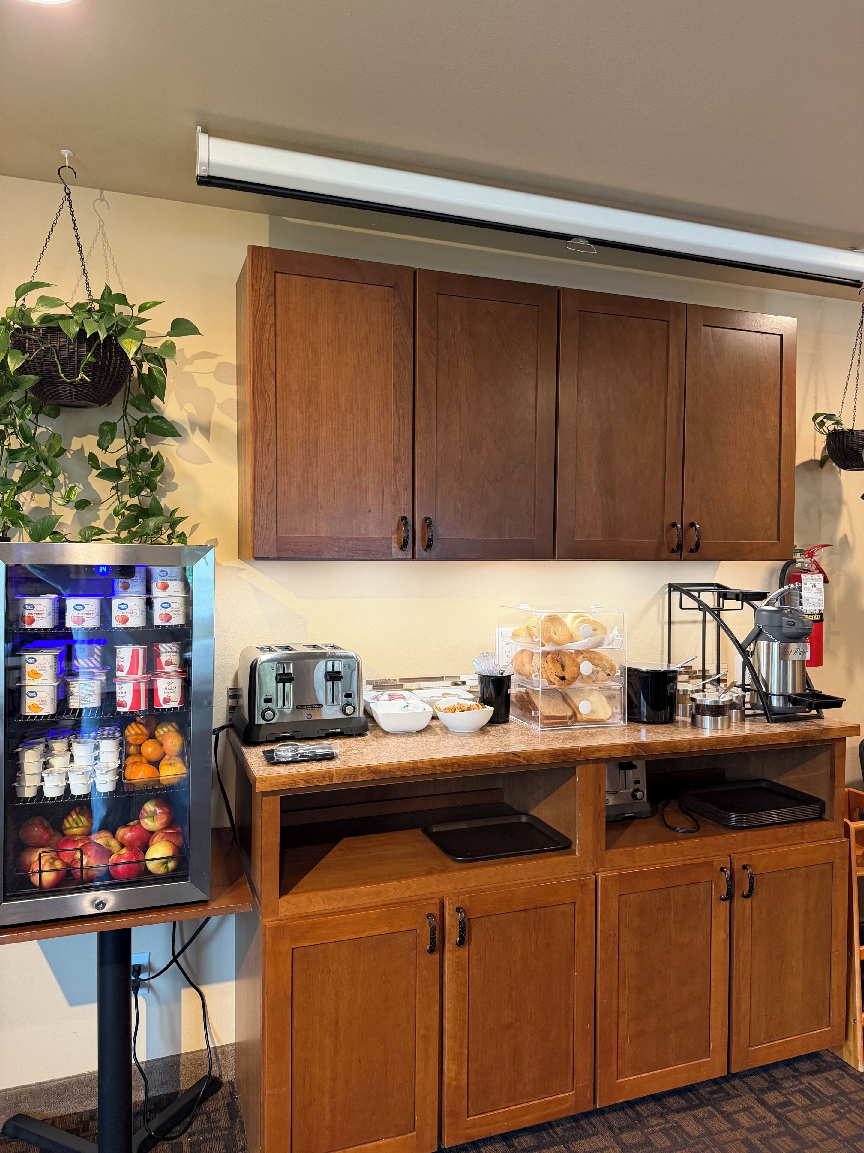 Una kitchenette con armarios de madera, un refrigerador lleno de comida, una cafetera y un tostador.