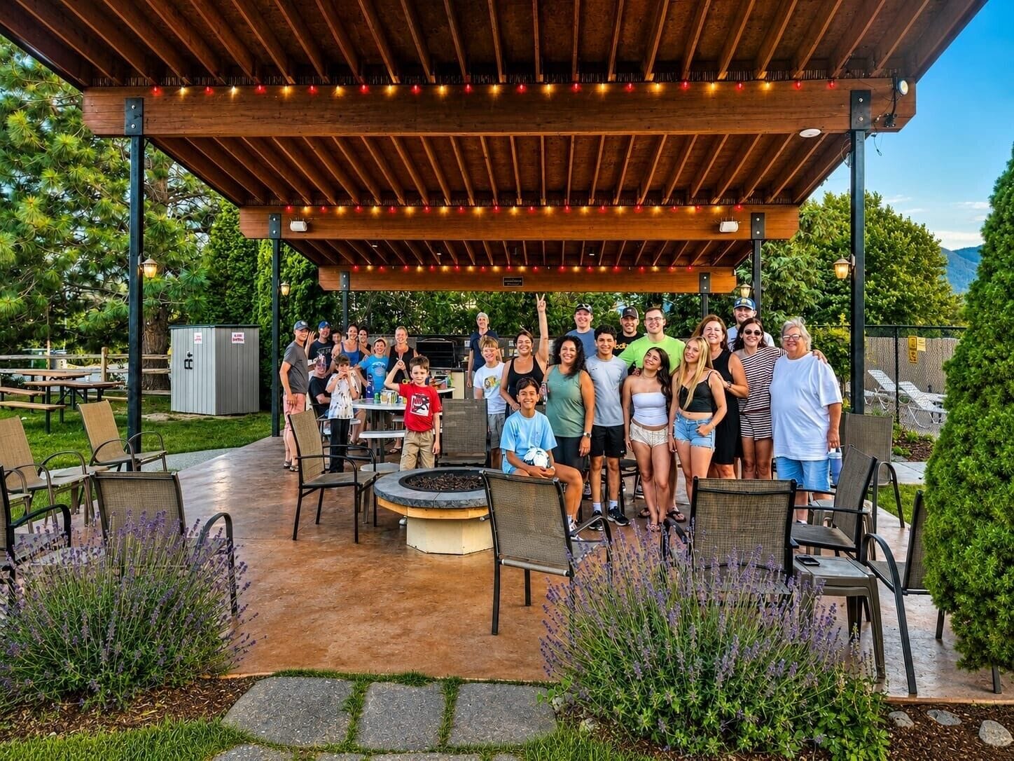 An outdoor patio area with a covered seating arrangement, a fire pit, and surrounding greenery.