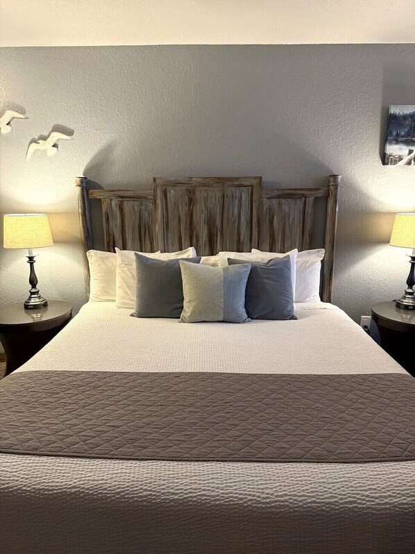 A neatly made bed with a quilted headboard and a variety of pillows.