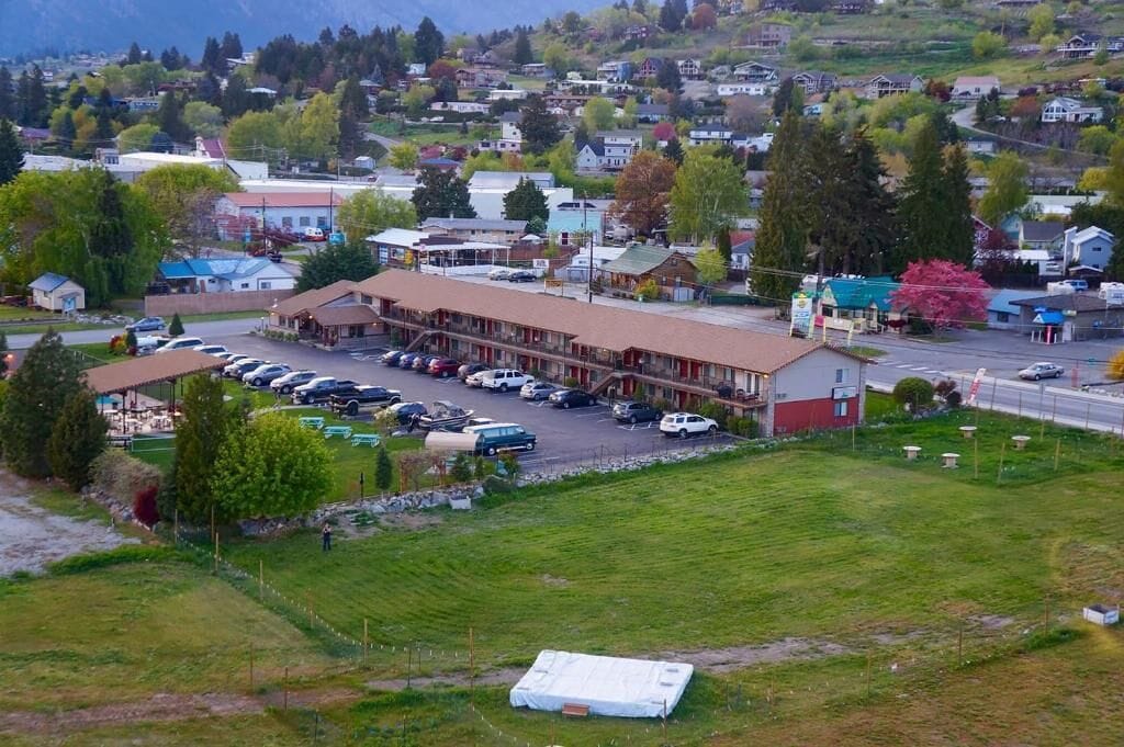 A motel with a parking lot and a building with a red roof.
