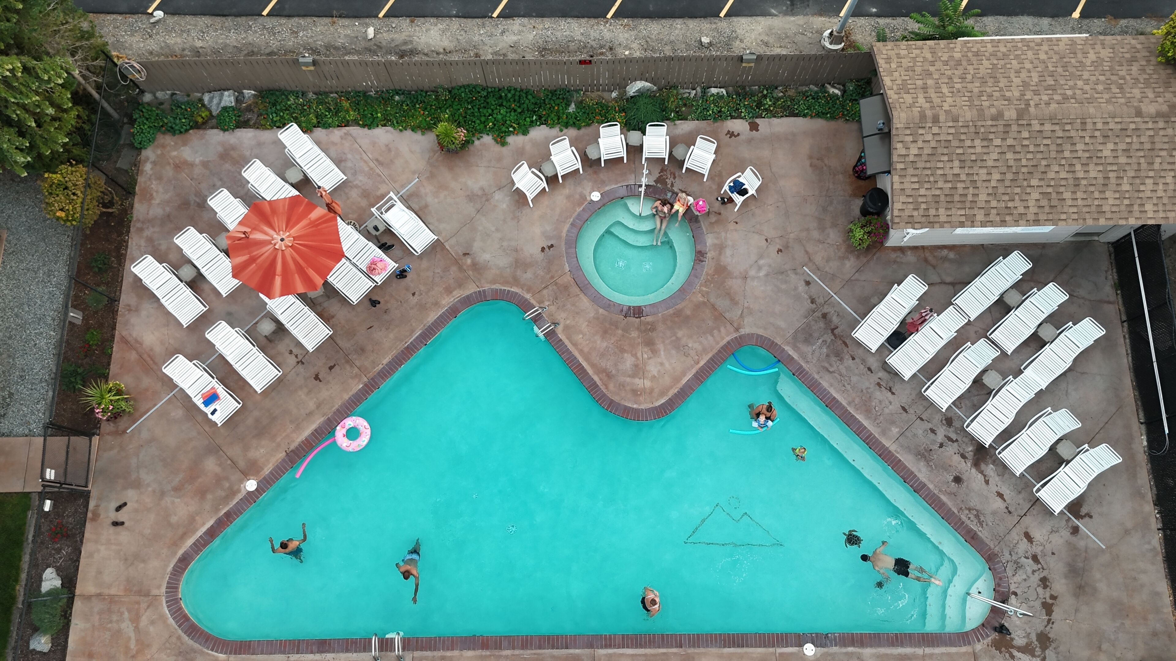 A swimming pool with multiple lanes, lounge chairs, and a small hot tub area.