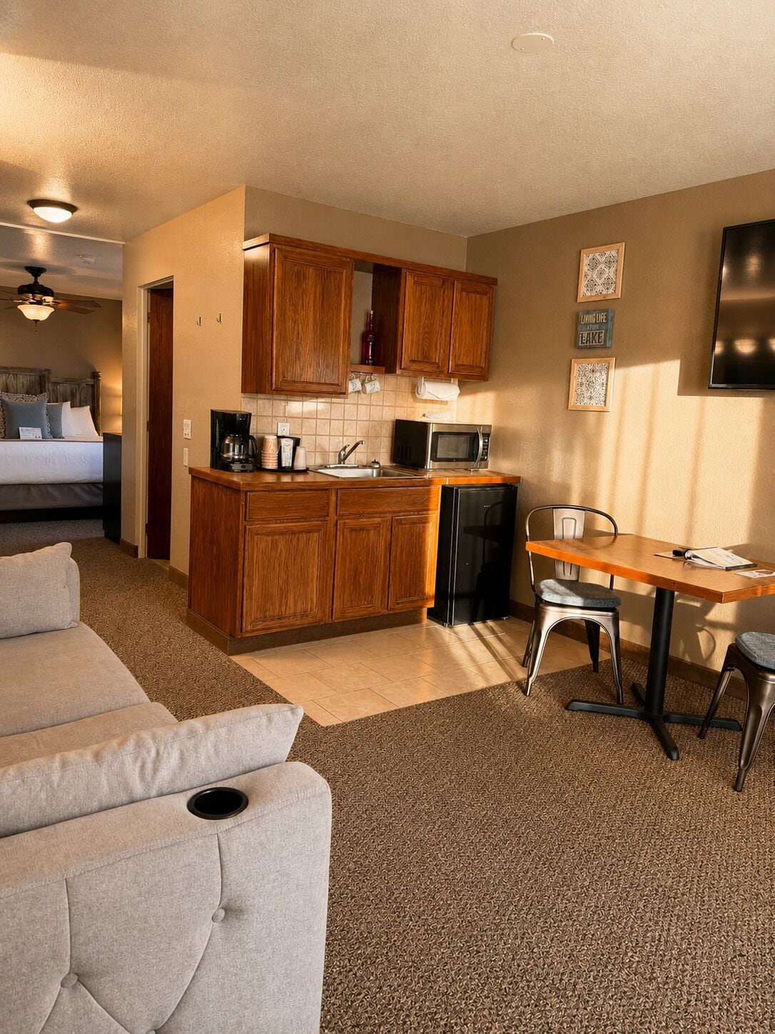 Un espacio habitable compacto con kitchenette, zona de comedor y sala de estar con sofá y sillas.