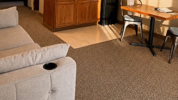 A compact living space with a kitchenette, a dining area, and a seating area with a sofa and chairs.