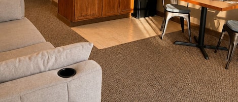 Un espacio habitable compacto con kitchenette, zona de comedor y sala de estar con sofá y sillas.