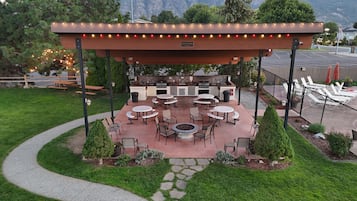 Eine Terrasse im Freien mit Grillbereich, Sitzgelegenheiten und einem Feuerkorb.
