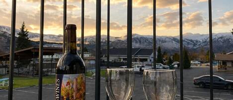 A balcony with a bottle of Malbec wine, two glasses, and a platter of cheese and crackers.