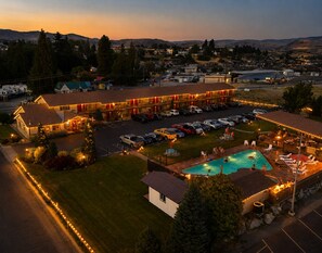 A hotel with a swimming pool, multiple parking spaces, and a view of the surrounding area.