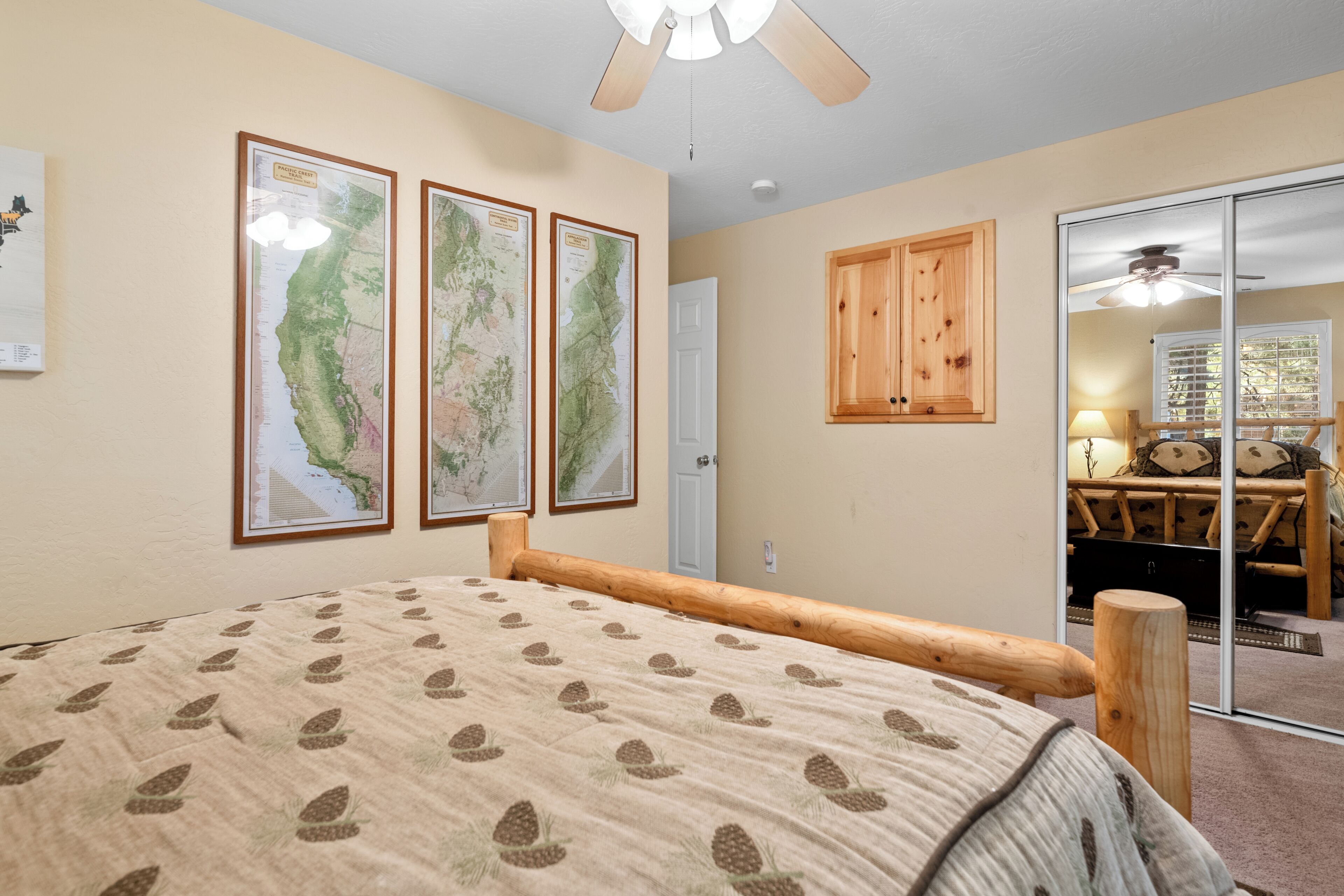 A bedroom with a bed, a wooden headboard, a ceiling fan, and a sliding glass door leading to a dining area.