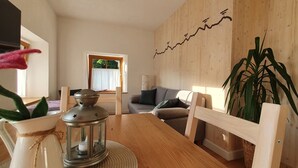 Un salón acogedor con una mesa de madera, un sofá y una planta grande.