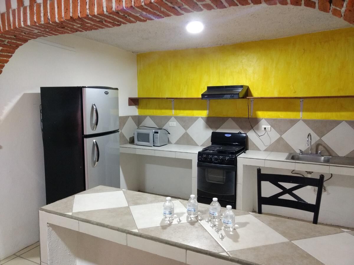 Cocina compacta con refrigerador, microondas, estufa y lavaplatos.