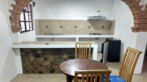 Une cuisine compacte avec un mur en pierre, une table à manger avec des chaises et une cuisinière intégrée.