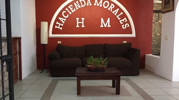 Un salon avec un mur rouge, un canapé marron, une table basse en bois et une plante en pot.