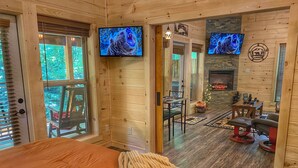 A cozy cabin interior with a bed, a dining area, and a fireplace.