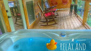 A hot tub with a duck float, wooden deck chairs, and a view of the outdoors.