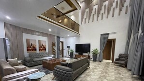 A modern living room with a sofa set, a coffee table, and a TV. - Golden Breeze Villa, Luxury 5-bedroom Villa with Private Pool (Accra)