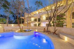 A modern building with a swimming pool, outdoor seating, and a well-lit staircase.