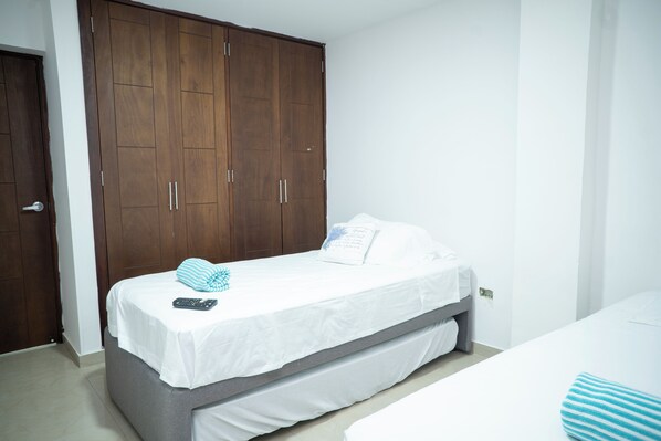 Un dormitorio con una cama individual, un armario de madera y una pared blanca.