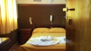 A hotel room with a bed, a nightstand, a lamp, and a wooden headboard. - Oasis (Mar del Plata)