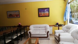A yellow-walled room with a dining table, two white sofas, and a glass-top coffee table. - Oasis (Mar del Plata)
