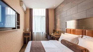 A hotel room with a large bed, a flat-screen TV mounted on the wall, a desk with a chair, and a window with curtains. - James Joyce Coffetel Hotel (Beijing Xizhimen Xinjiekou Subway) (Beijing)