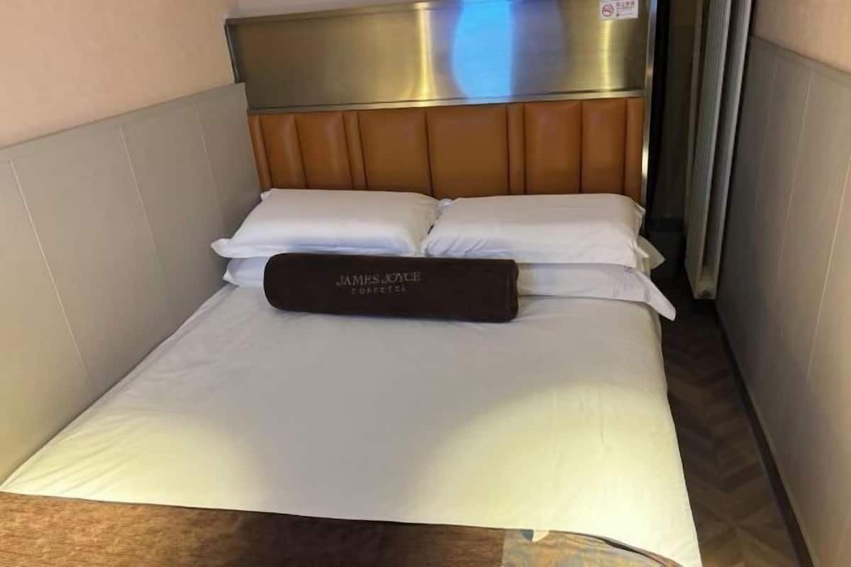 Ein Hotelzimmer mit einem Bett, einem Kopfteil und einem Kopfkissen mit dem Aufdruck 'James Joyce'.