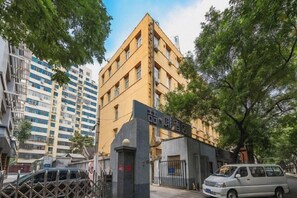 A multi-story building with a prominent entrance gate, surrounded by trees. - James Joyce Coffetel Hotel (Beijing Xizhimen Xinjiekou Subway) (Beijing)
