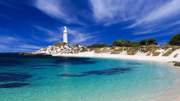 A beach with clear turquoise waters, a white sandy shore, and a lighthouse on a rocky outcrop. - Coastal convenience - 2 min walk to shops & cafes (Scarborough)