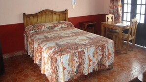 A bedroom with a bed, a desk, and a chair. - Hotel Virreyes (Puebla)