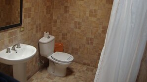 A bathroom with a sink, toilet, and shower curtain. - Hotel Virreyes (Puebla)
