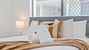 A neatly made bed with a brown blanket, white pillows, and a folded white towel. - Coastal Elegance! A Luxurious, Dreamy Escape! (Scarborough)
