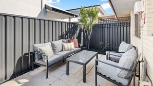 An outdoor patio area with a sofa, two chairs, and a table. - Coastal Elegance! A Luxurious, Dreamy Escape! (Scarborough)