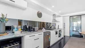 Uma cozinha moderna com forno embutido, lava-louças e uma ilha grande com pia.