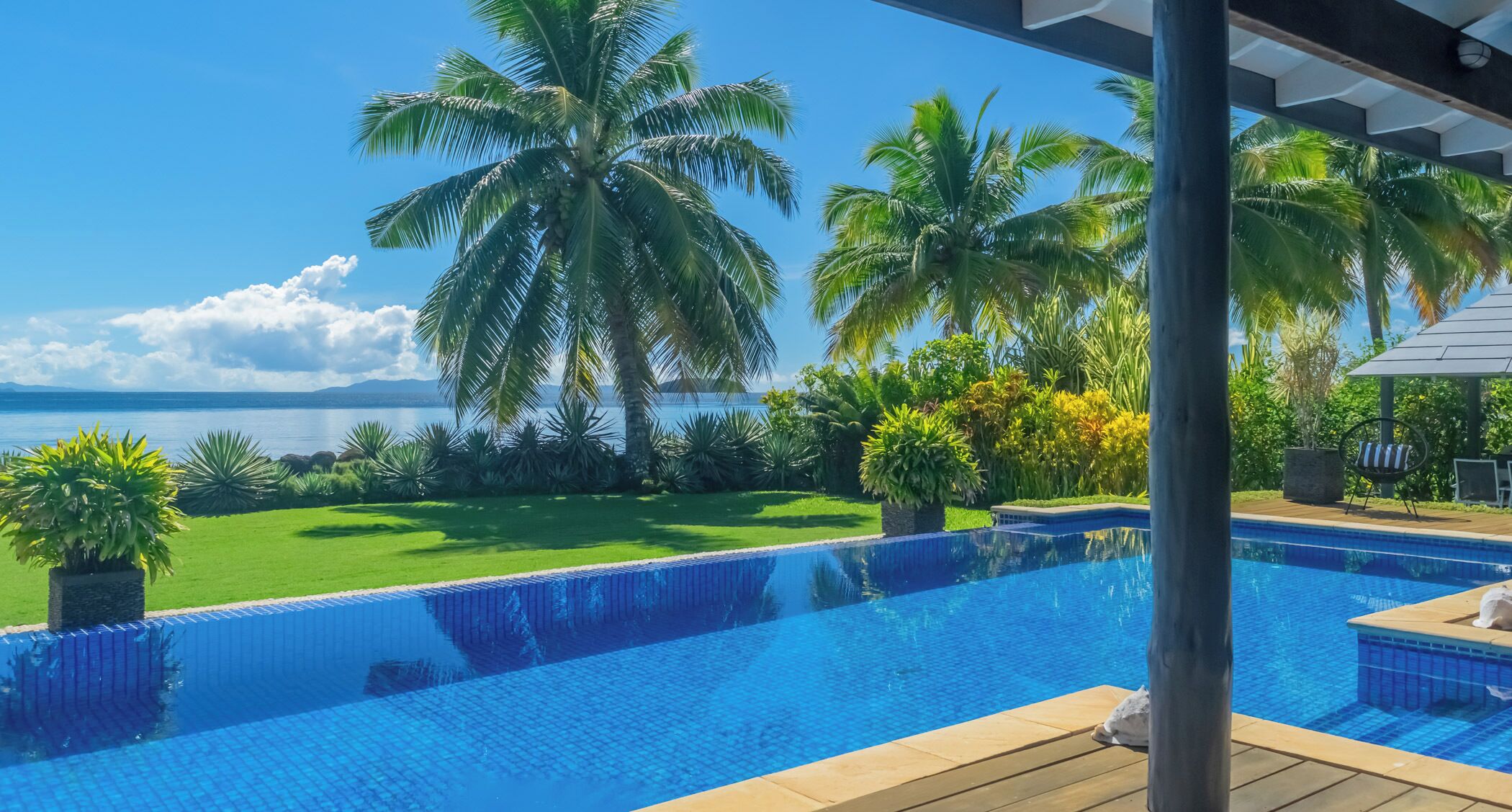 Piscina con vista al mar y palmeras.