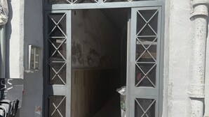 A doorway with a geometric pattern, a metal door handle, and a small trash bin to the right.